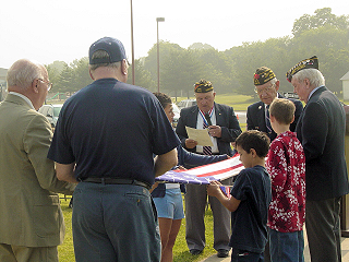 Members of Anthony T. Calista VFW Post 5579 along with East Greenwich students hold a flag folding ceremony.
